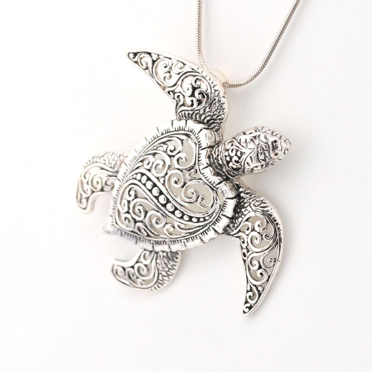 Silver turtle pendant necklace on a white background