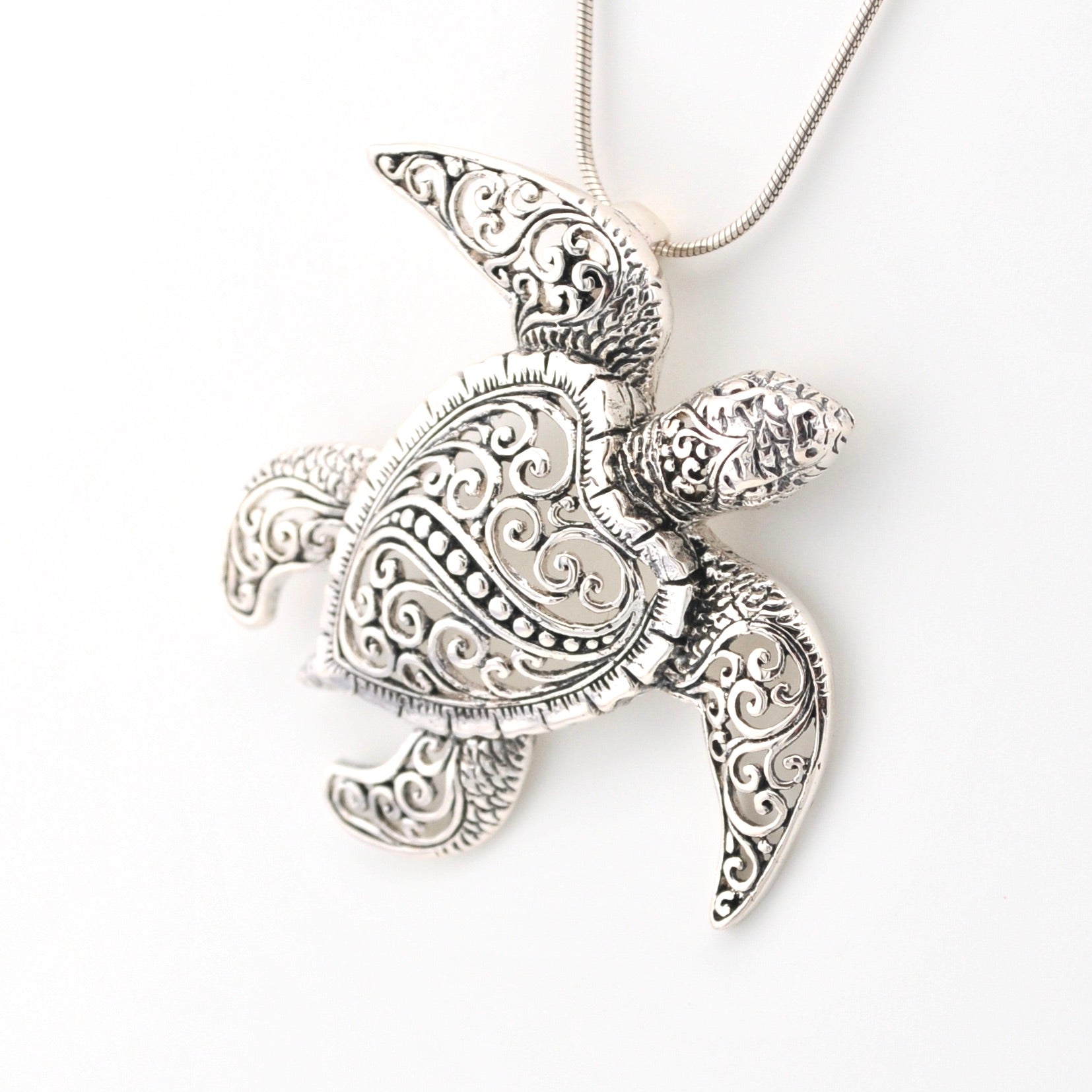 Silver turtle pendant necklace on a white background