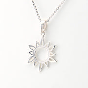 Silver sun-shaped pendant necklace on a white background