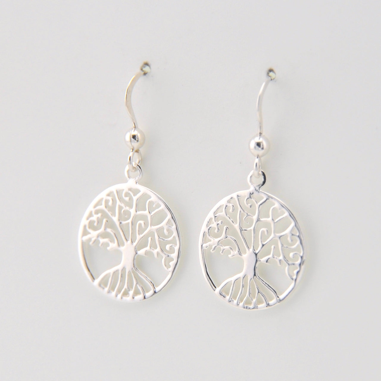 Silver tree-shaped earrings on a light gray background