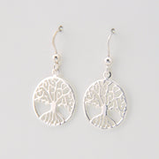 Silver tree-shaped earrings on a light gray background