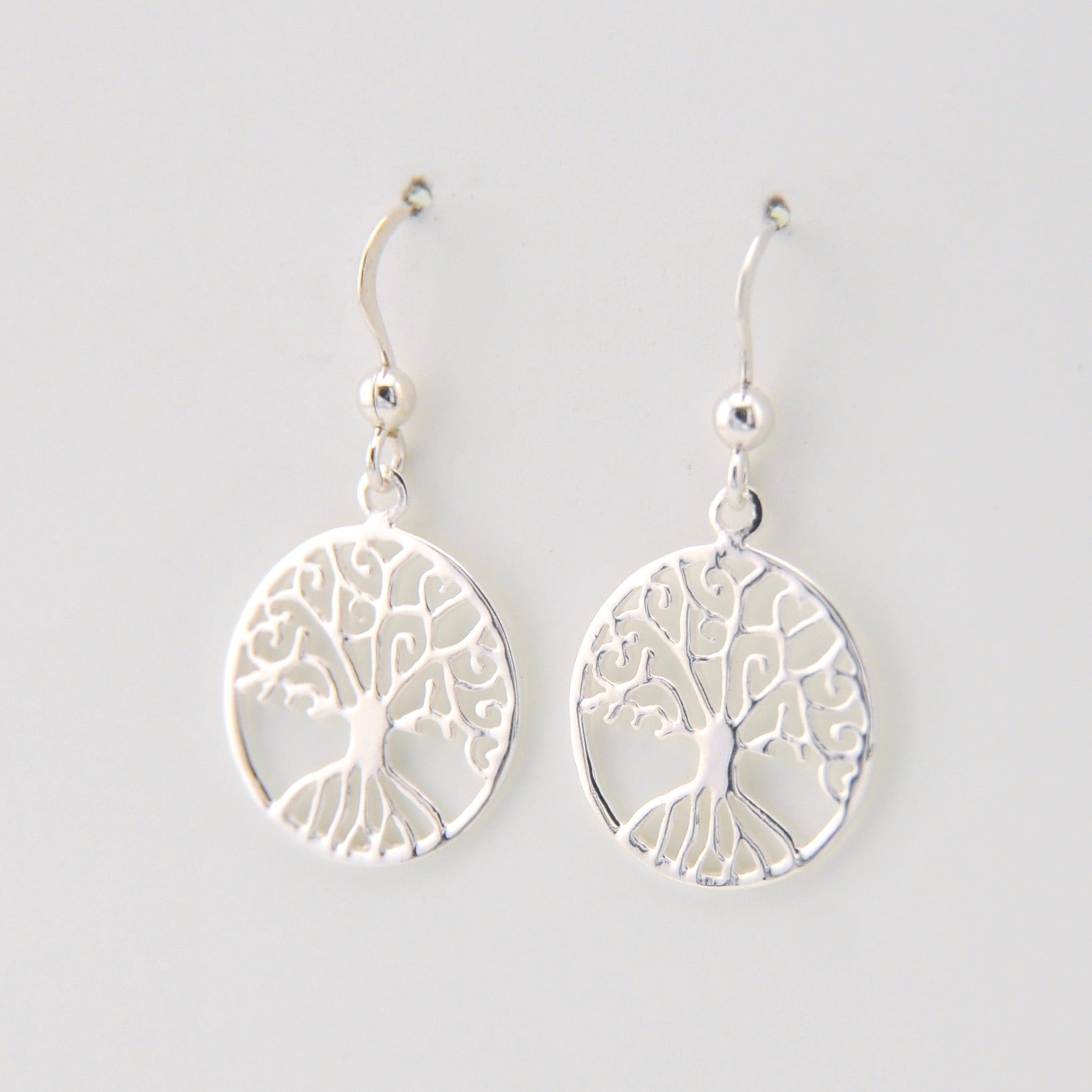 Silver tree-shaped earrings on a light gray background
