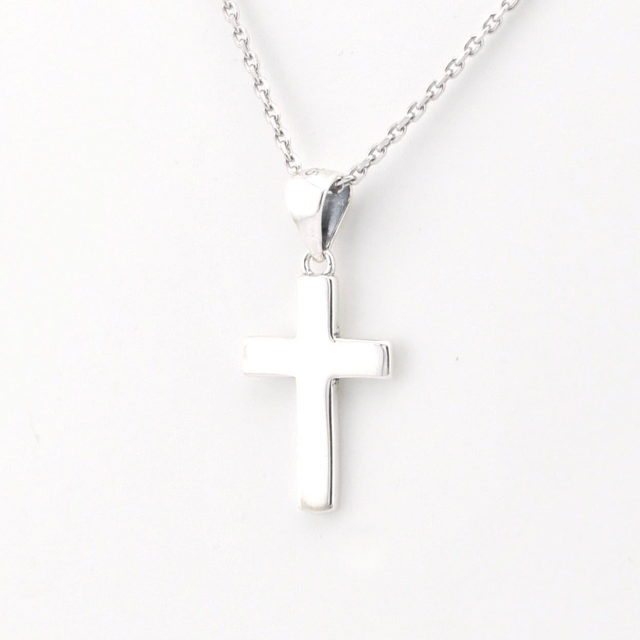 Silver cross necklace on a white background