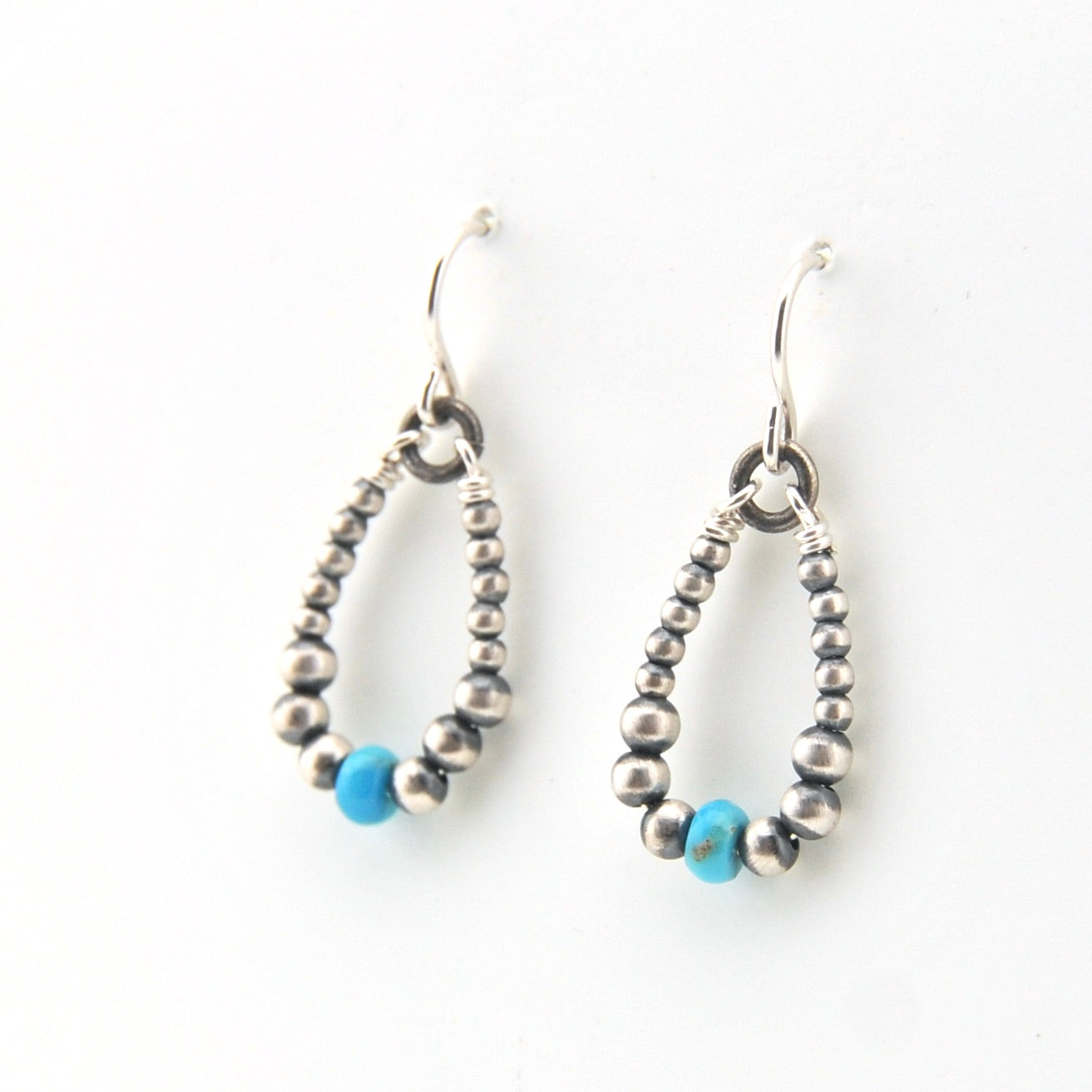 Pair of silver beaded earrings with blue beads on a white background