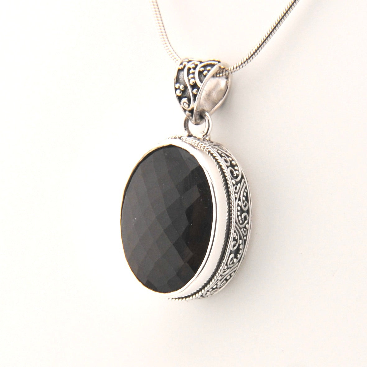 Silver pendant with a brown stone on a white background