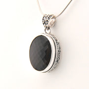 Silver pendant with a brown stone on a white background