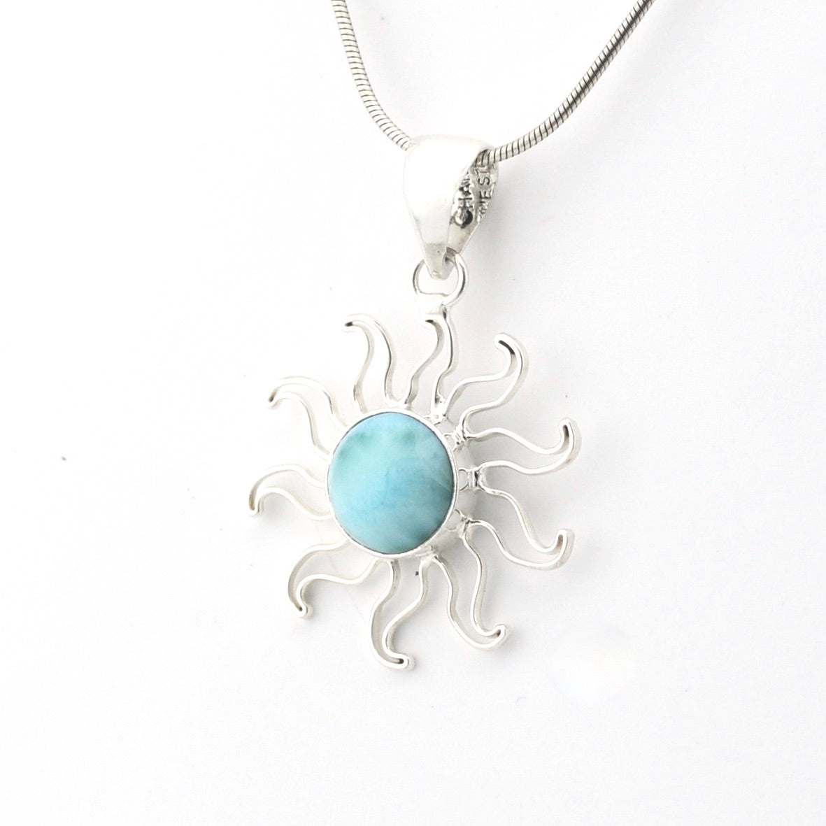 Silver sun-shaped pendant with a blue stone on a white background