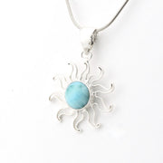Silver sun-shaped pendant with a blue stone on a white background