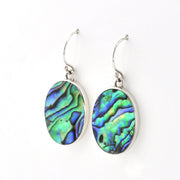 A pair of silver drop earrings featuring oval abalone shell pendants with vibrant green, blue, and purple iridescent patterns, set against a plain white background.