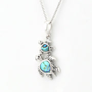 A sterling silver pendant necklace featuring a mother-and-child turtle design, detailed with iridescent blue abalone shell inlays on the turtle shells, shown on a white background.