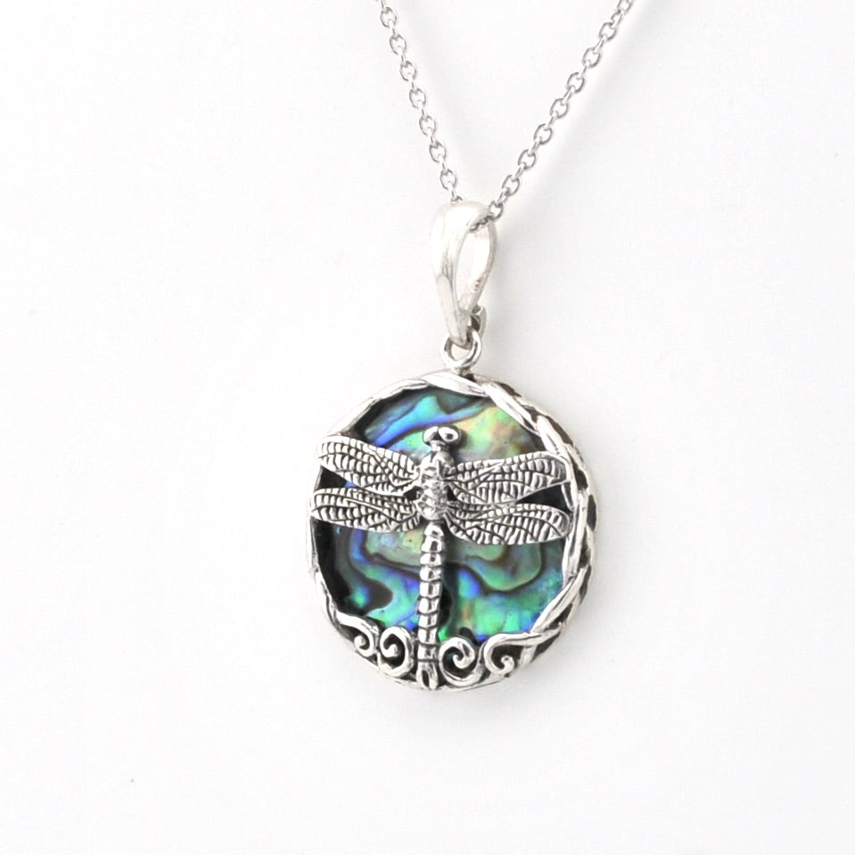 A silver dragonfly pendant necklace featuring a detailed dragonfly over an iridescent abalone shell inlay, suspended from a delicate silver chain against a plain white background.