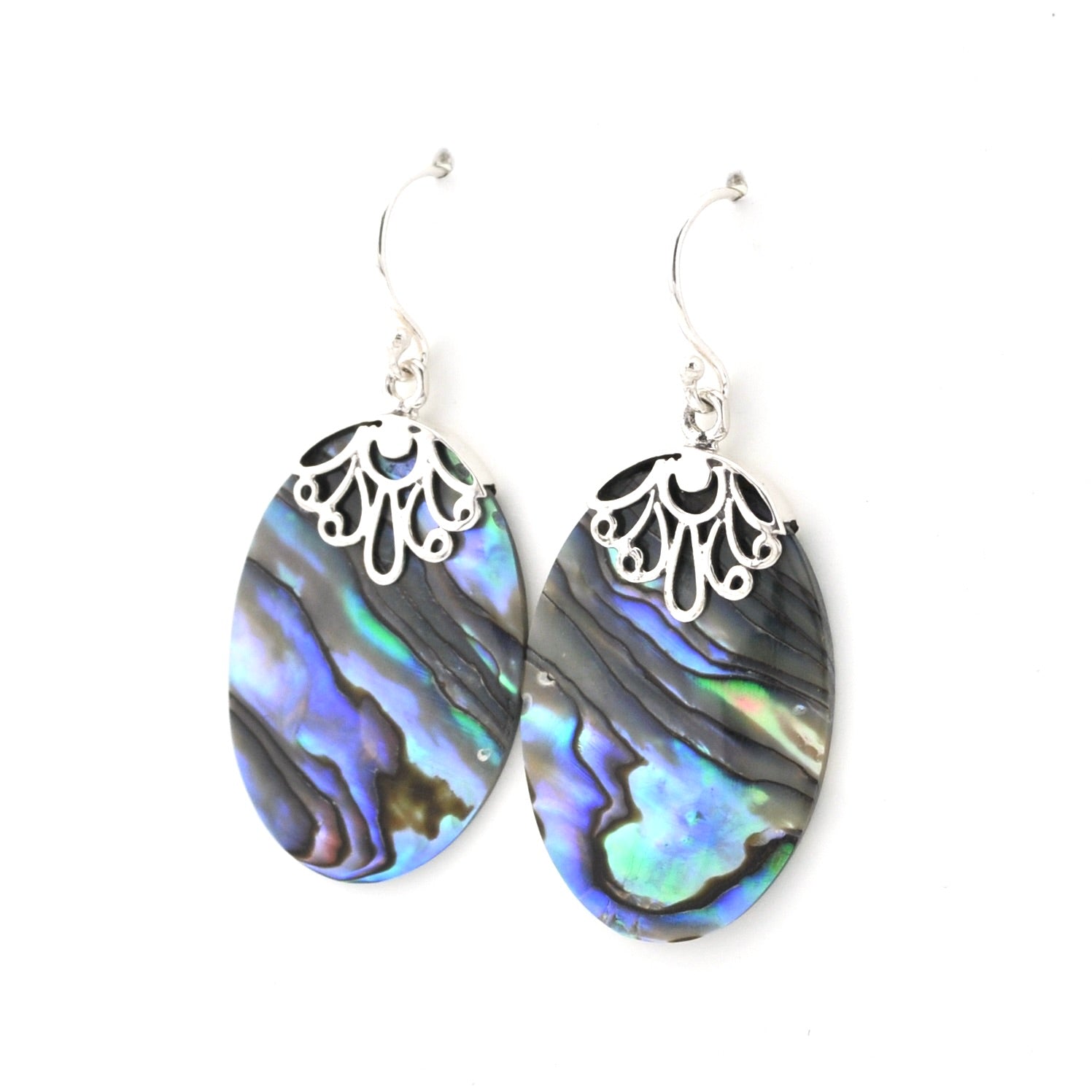 A pair of dangle earrings featuring oval abalone shell with iridescent blue, green, and black patterns, suspended from silver filigree caps and silver fishhook wires, shown against a plain white background.