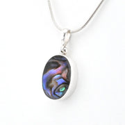 An oval pendant necklace featuring a silver bezel-set iridescent abalone shell inlay with blue, purple, and green hues, suspended from a silver snake chain against a plain white background.