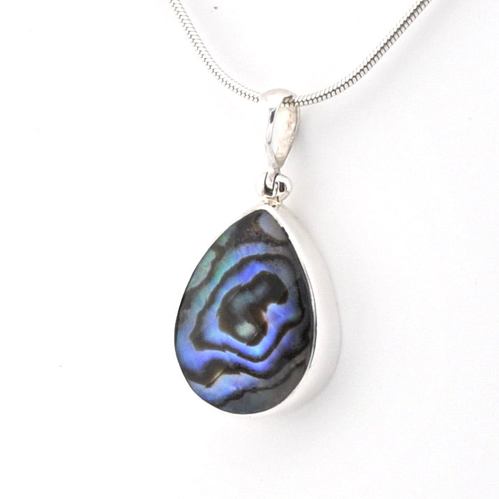 A silver teardrop pendant necklace featuring a vibrant blue and black iridescent abalone shell inlay, suspended from a silver snake chain against a plain white background.