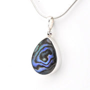A silver teardrop pendant necklace featuring a vibrant blue and black iridescent abalone shell inlay, suspended from a silver snake chain against a plain white background.