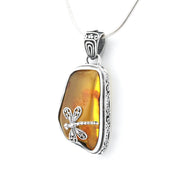 A silver dragonfly pendant necklace featuring a polished amber-colored stone with orange inclusions, set in an ornate silver bezel on a silver snake chain.