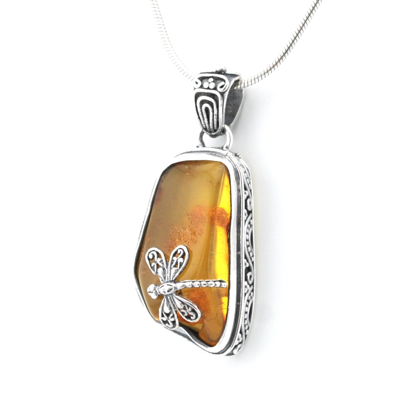 A silver dragonfly pendant necklace featuring a polished amber-colored stone with orange inclusions, set in an ornate silver bezel on a silver snake chain.