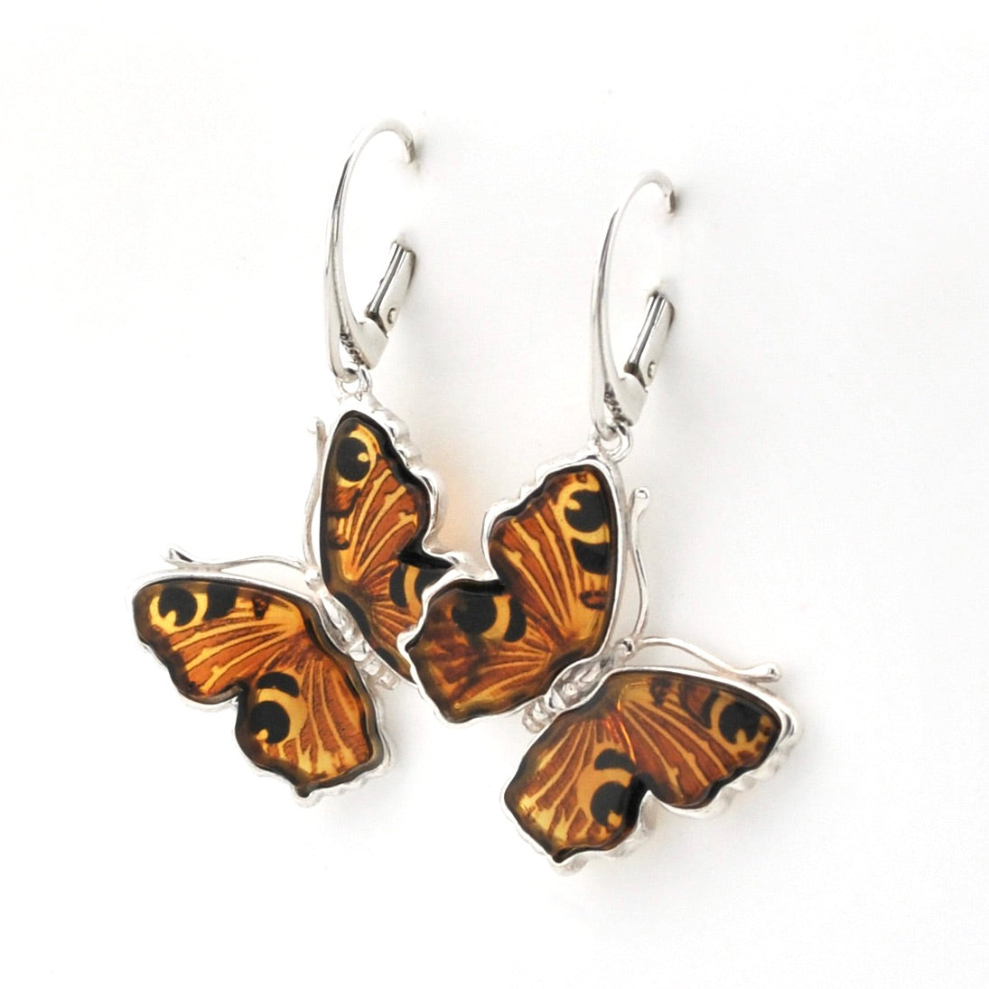 A pair of butterfly-shaped dangle earrings with orange and black patterned wings set in silver-tone metal hooks, shown on a plain white background.