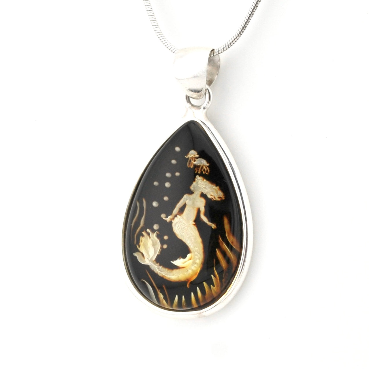 A teardrop-shaped pendant necklace featuring a mermaid design on a black background with gold and white details, set in a silver-tone frame and suspended from a silver chain.