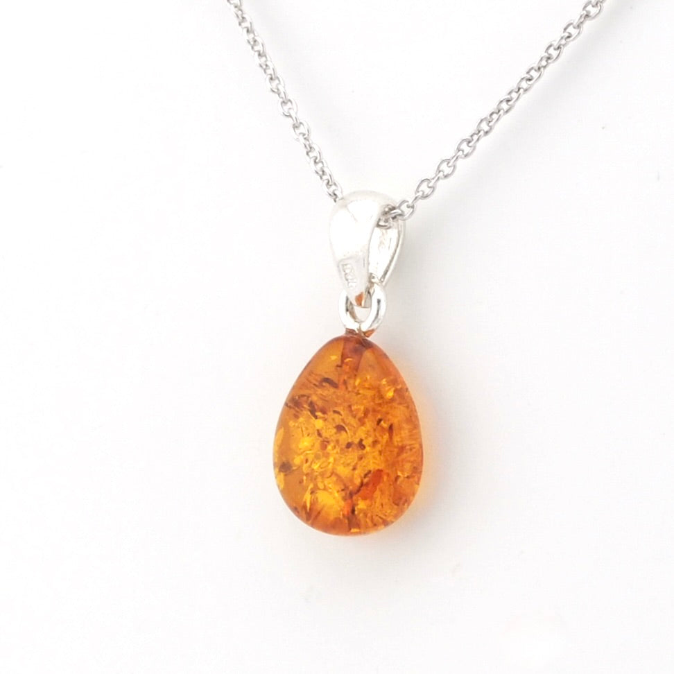 A teardrop-shaped amber pendant necklace on a delicate silver chain, set against a plain white background.