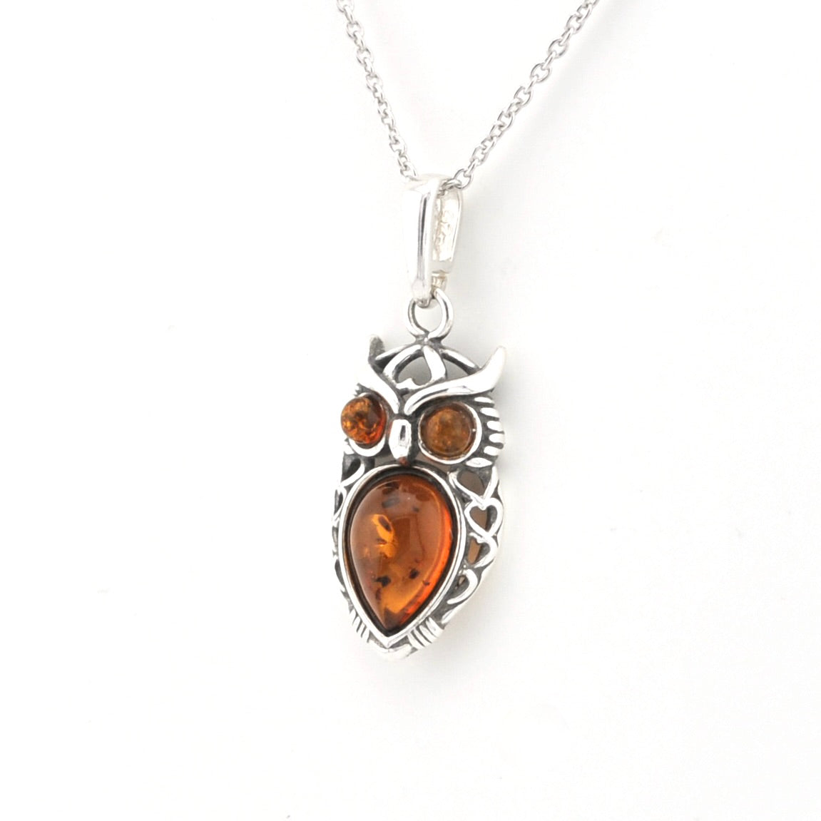 A silver owl pendant necklace featuring a large teardrop-shaped amber gemstone in the center and two smaller round amber stones for the eyes, suspended from a silver chain against a plain white background.