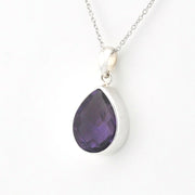 A silver pendant necklace featuring a teardrop-shaped purple gemstone, shown against a plain white background.