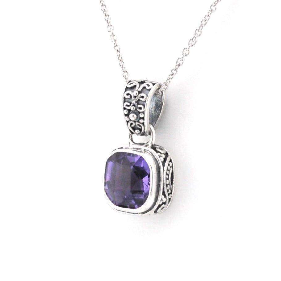 A silver pendant necklace featuring a square-cut purple gemstone in an ornate silver bezel setting, suspended from a delicate silver chain against a plain white background.