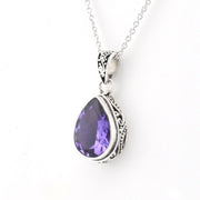 A silver teardrop pendant necklace featuring a faceted purple gemstone, set in an ornate silver bezel with a delicate silver chain against a plain white background.