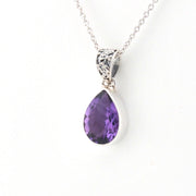 A silver teardrop pendant necklace featuring a faceted purple gemstone, suspended from a delicate silver chain against a plain white background.