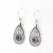 Teardrop-shaped silver earrings with purple gemstones on a white background