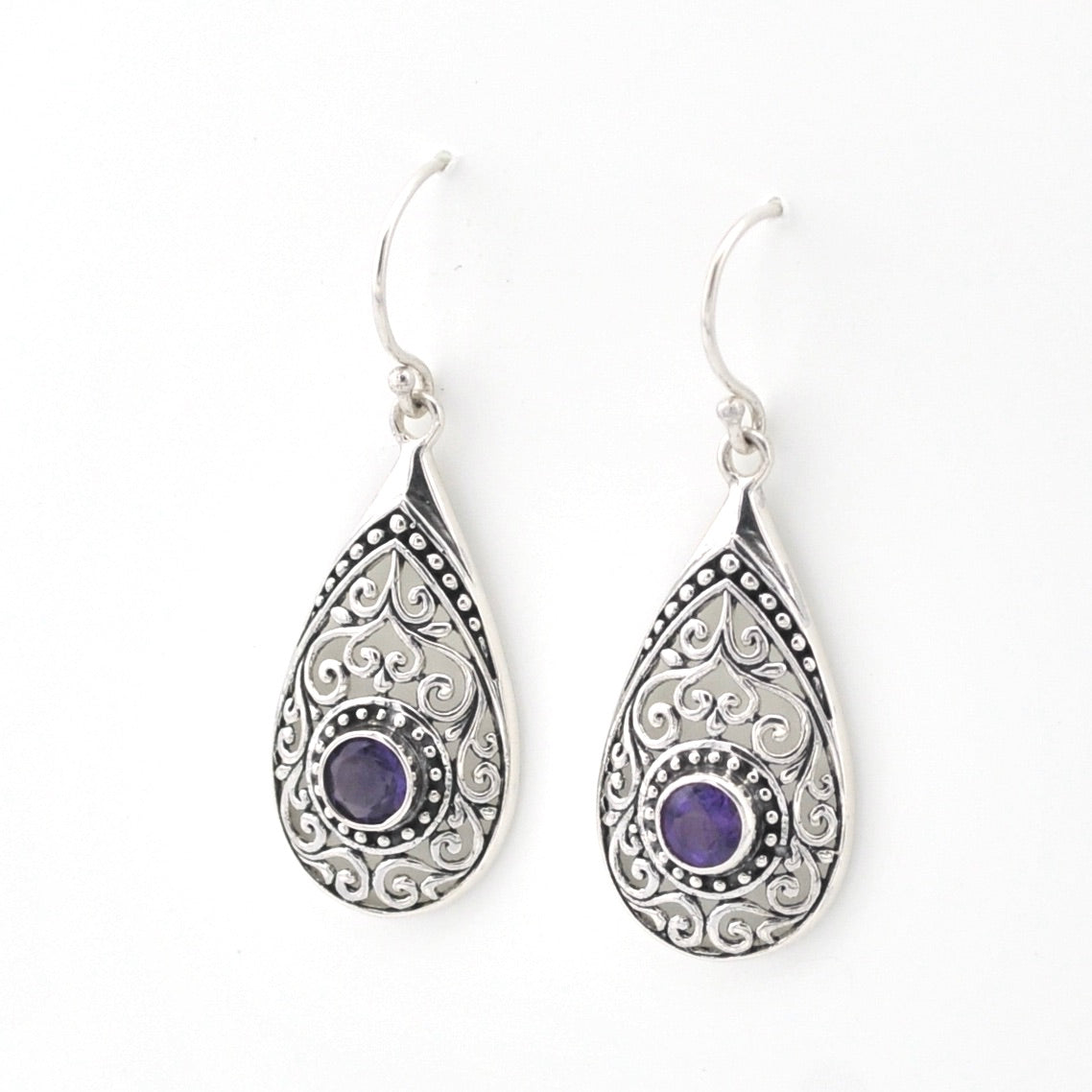 Teardrop-shaped silver earrings with purple gemstones on a white background