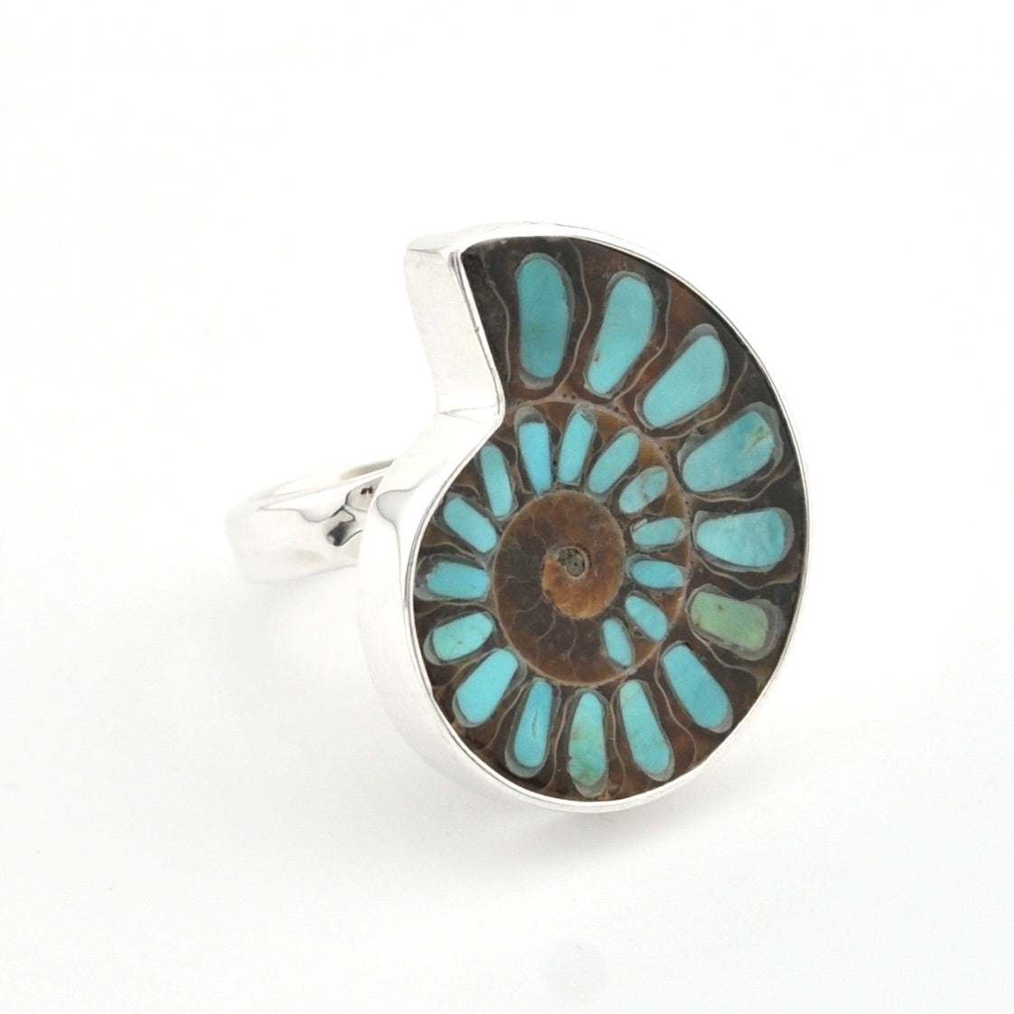 A silver ring featuring a large, stylized spiral inlay of brown fossilized ammonite with light blue turquoise-like segments, shown on a plain white background.