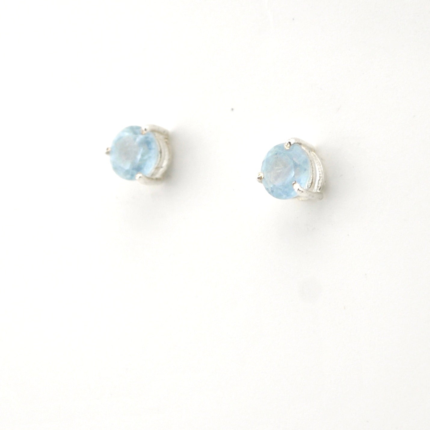 Pair of silver earrings with light blue gemstones on a white background