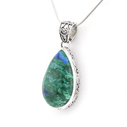 A teardrop-shaped pendant necklace featuring a green azurite gemstone with blue flashes, set in an ornate silver bezel with a matching silver chain.