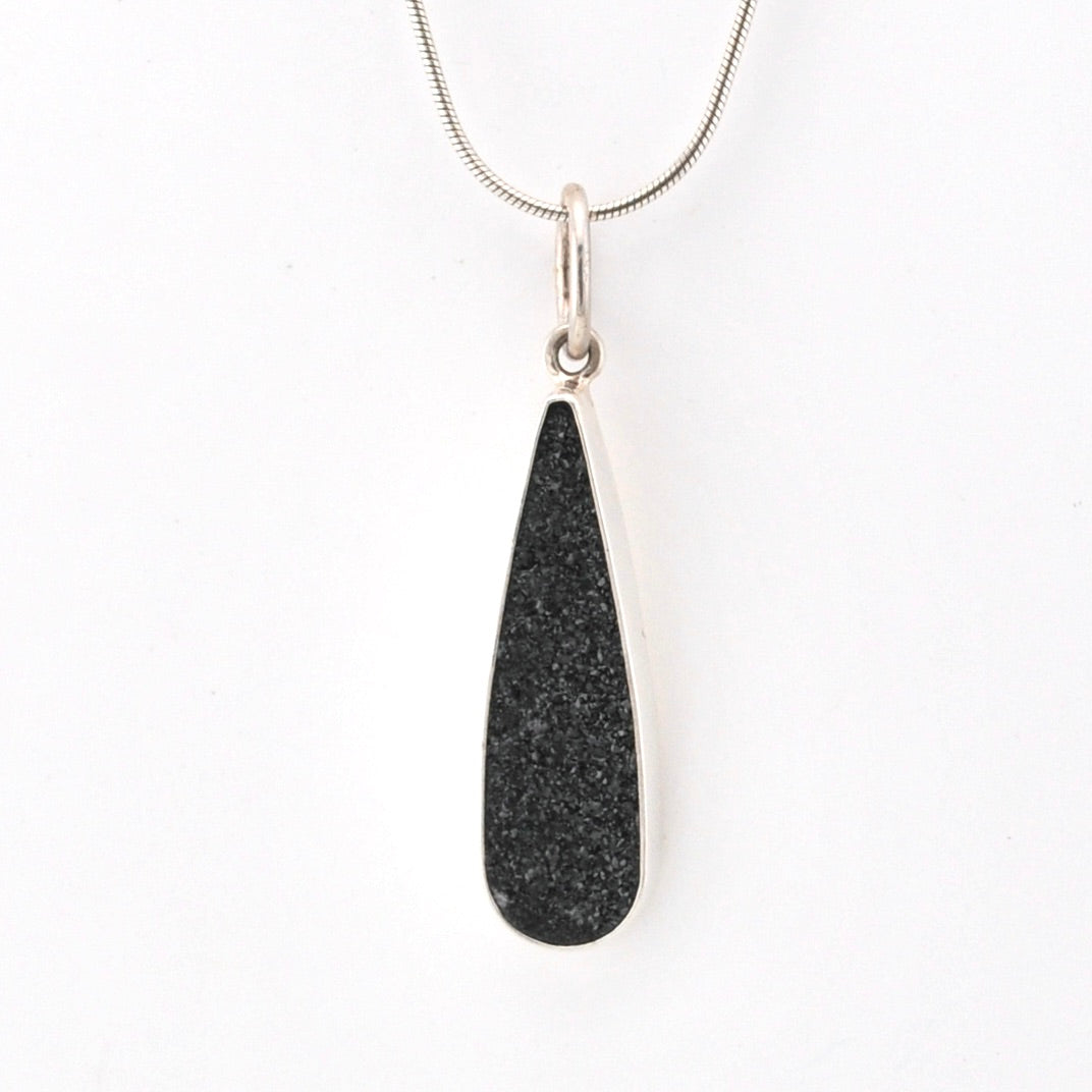 Black teardrop pendant on a silver chain against a white background