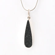 Black teardrop pendant on a silver chain against a white background