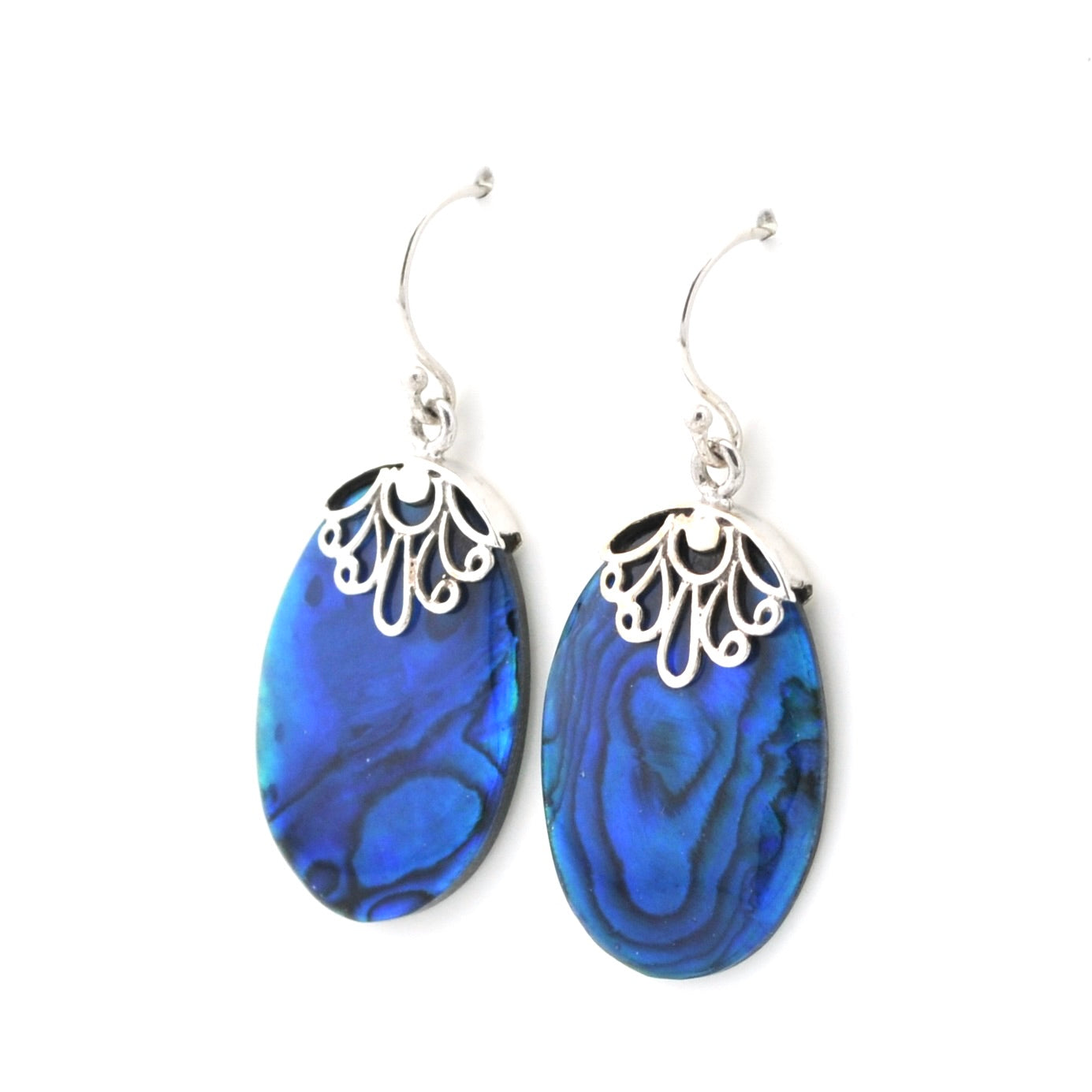A pair of dangle earrings featuring oval blue iridescent abalone shell pendants with silver filigree caps and silver French hook ear wires, shown against a plain white background.