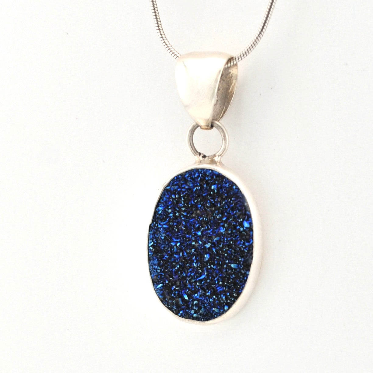 Blue druzy pendant on a silver chain against a white background