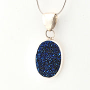 Blue druzy pendant on a silver chain against a white background