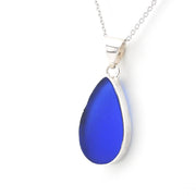 A teardrop-shaped sea glass pendant necklace in vibrant blue with a polished silver bezel and chain, shown on a clean white background.