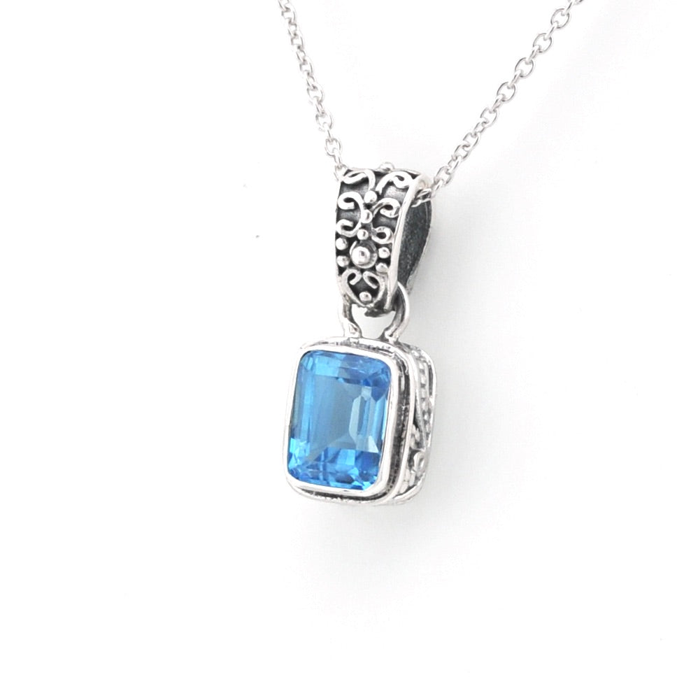 A silver pendant necklace featuring a rectangular blue gemstone in a silver bezel setting with an ornate silver bail, shown on a white background.