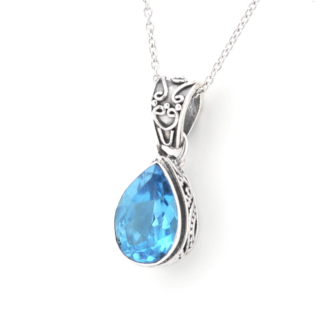 A silver pendant necklace featuring a teardrop-shaped light blue gemstone in an ornate silver setting, suspended from a delicate silver chain against a plain white background.