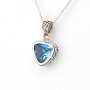 A silver pendant necklace featuring a triangular blue gemstone in a textured silver bezel setting, suspended from a silver chain against a plain white background.