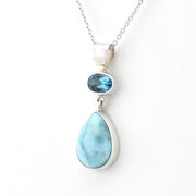 A silver pendant necklace featuring a large teardrop-shaped light blue larimar stone and a smaller oval blue topaz stone, shown on a white background.