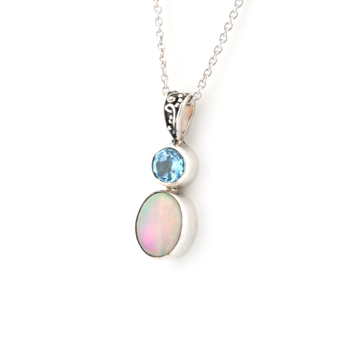 Silver necklace with a pendant featuring an opal and blue gemstone on a white background