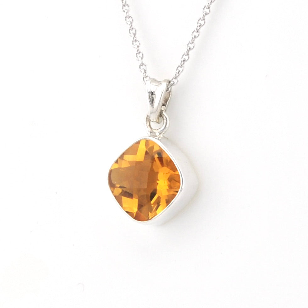 A silver pendant necklace featuring a faceted, rounded amber-orange gemstone in a silver bezel setting, suspended from a delicate silver chain against a plain white background.