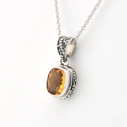 Silver pendant with a yellow gemstone on a white background