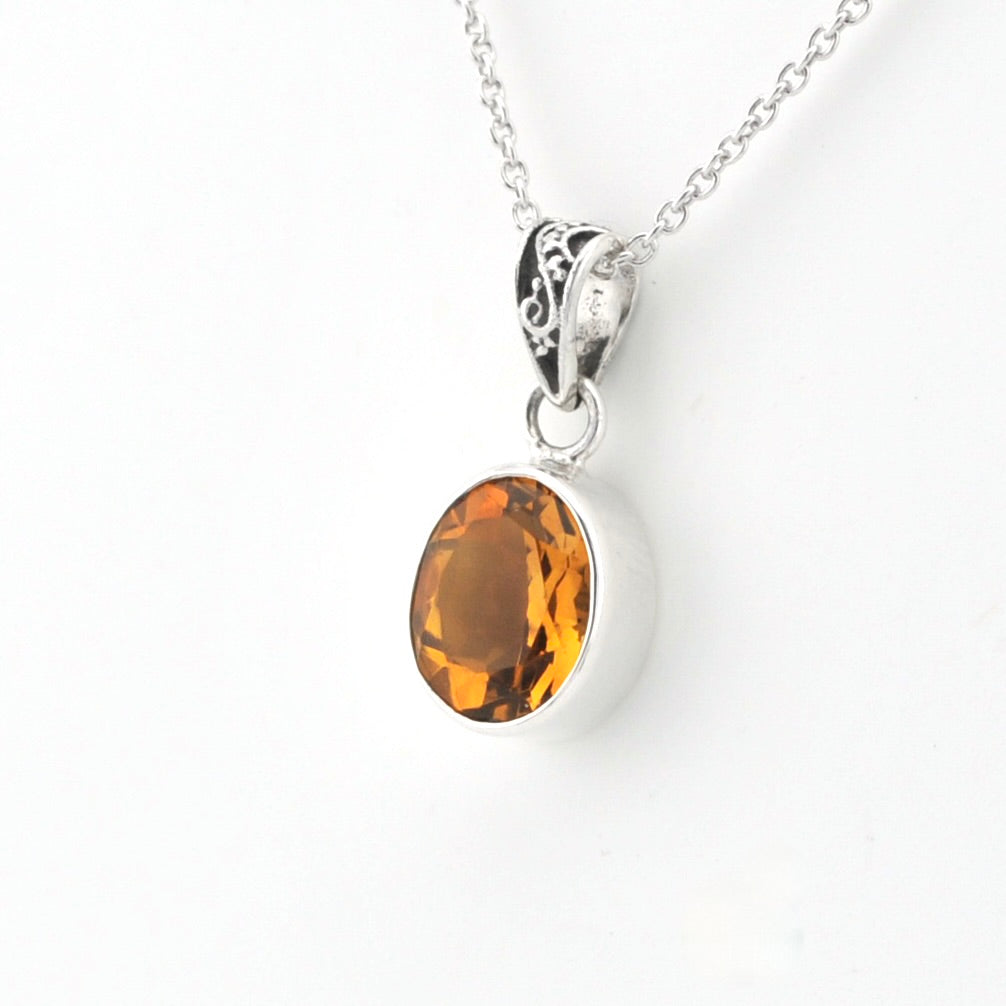 An oval-cut amber gemstone pendant set in a silver bezel with a silver chain, shown against a plain white background.