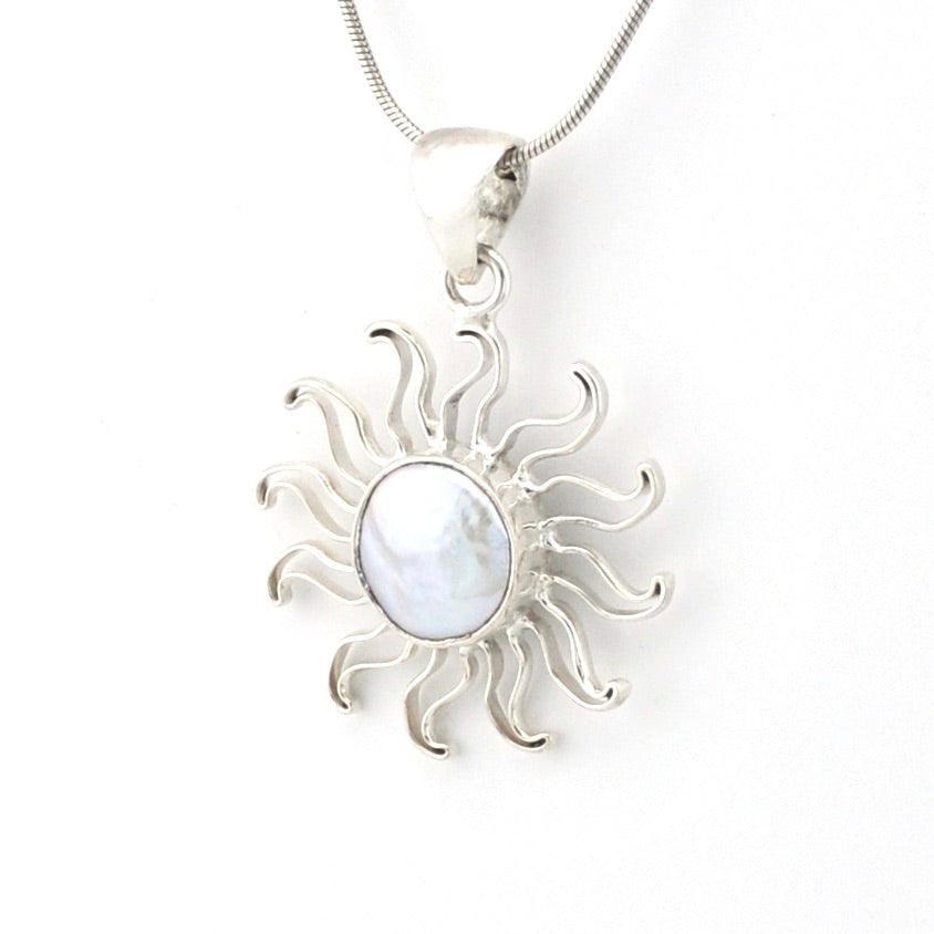 Silver sun-shaped pendant with a central gemstone on a white background