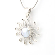 Silver sun-shaped pendant with a central gemstone on a white background